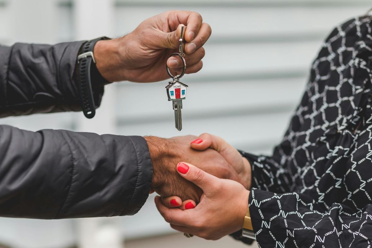 person handing a key to the new owner of the house